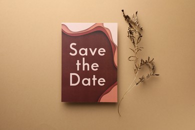 Beautiful card with Save the Date phrase and dry branch on beige background, top view