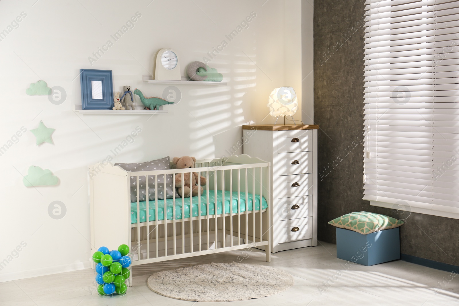 Photo of Cute nursery interior with comfortable crib near white wall