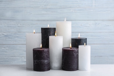 Set of burning candles on table against light wooden background