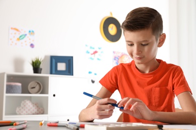 Little child drawing picture at table in room. Space for text