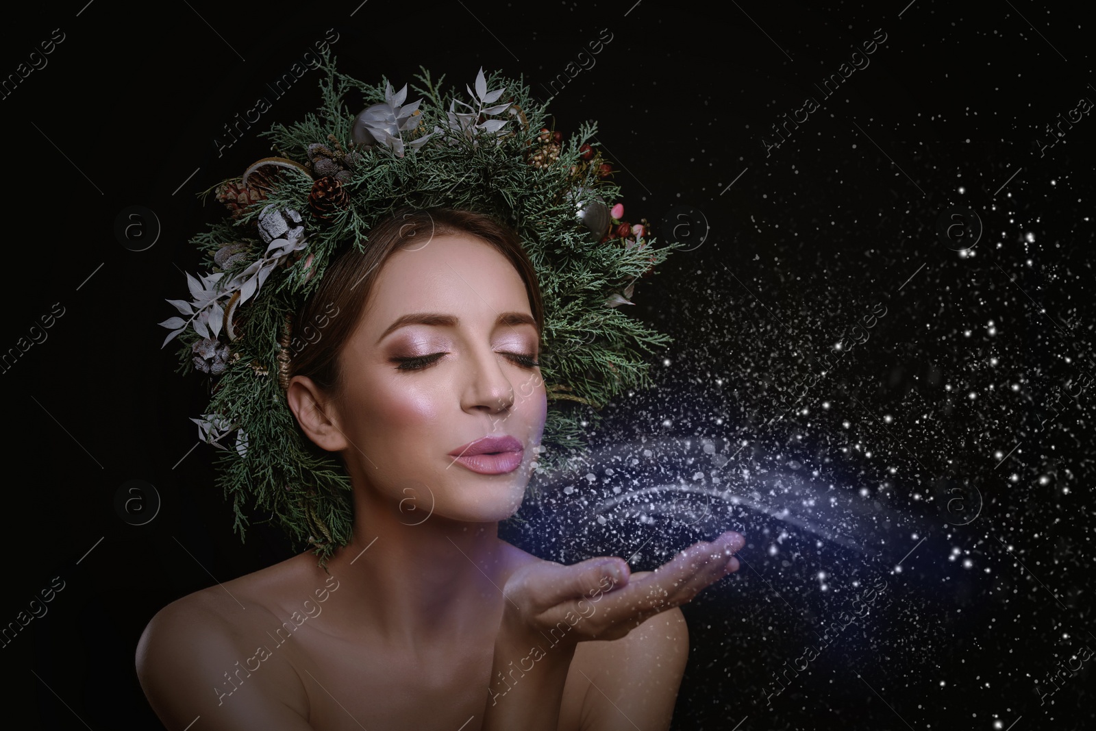 Image of Beautiful young woman with Christmas wreath blowing kiss on black background