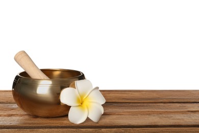 Golden singing bowl, mallet and flower on wooden table against white background, space for text