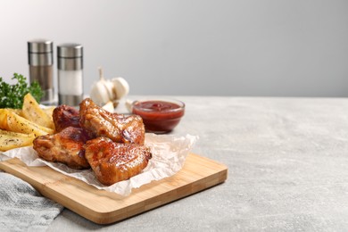 Photo of Delicious fried chicken wings served on light grey table, space for text