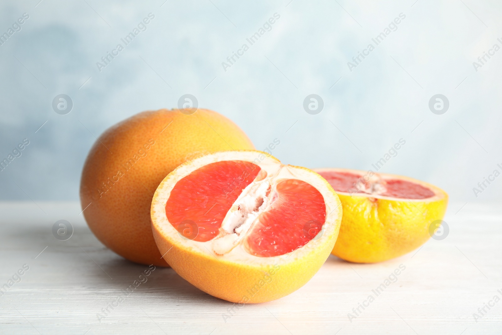 Photo of Fresh tasty grapefruits on table against color background