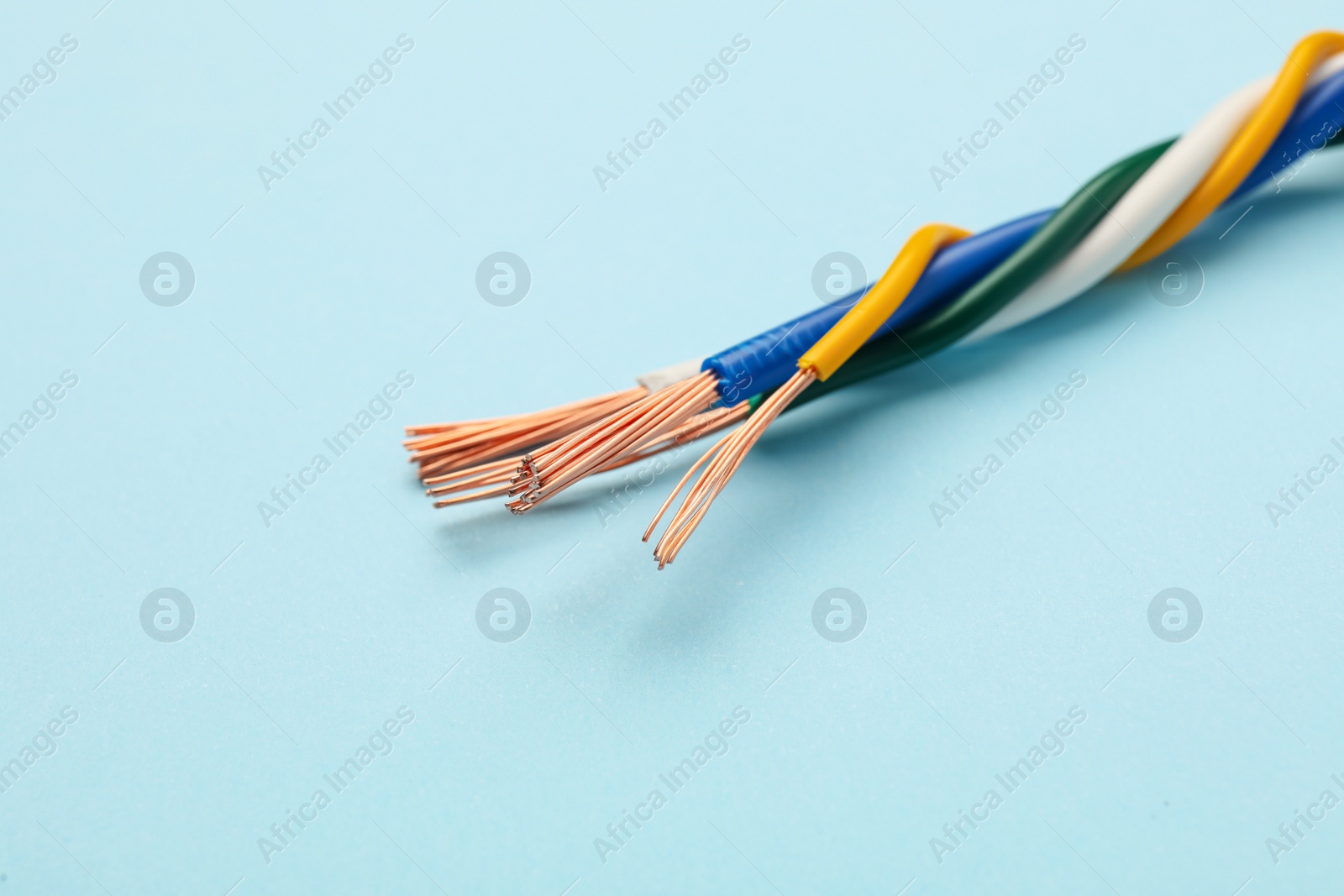 Photo of Many stripped electrical wires on light blue background, closeup