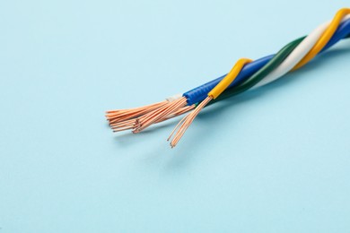 Photo of Many stripped electrical wires on light blue background, closeup