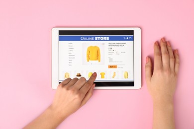 Photo of Woman with tablet shopping online on pink background, top view