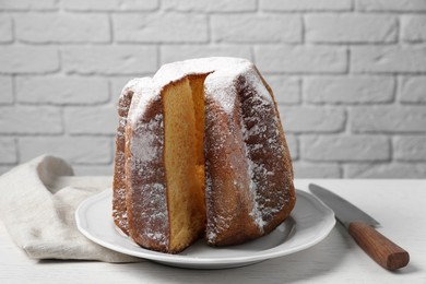Delicious Pandoro cake decorated with powdered sugar on white table. Traditional Italian pastry