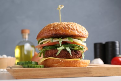 Board with delicious vegetarian burger on white table, closeup