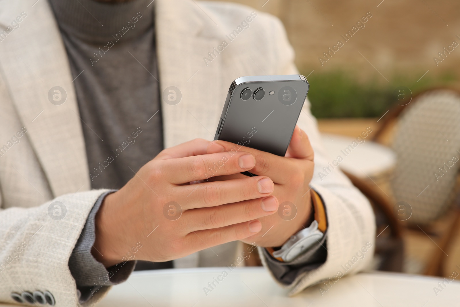 Photo of Man using smartphone at table in outdoor cafe, closeup