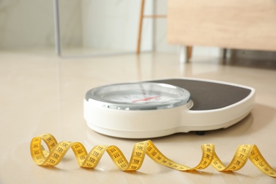 Photo of Scales and measuring tape on floor in bathroom. Overweight problem