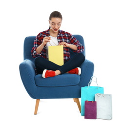 Young woman with shopping bags sitting in armchair on white background