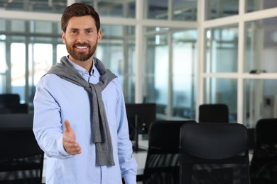 Photo of Happy man welcoming and offering handshake in office, space for text