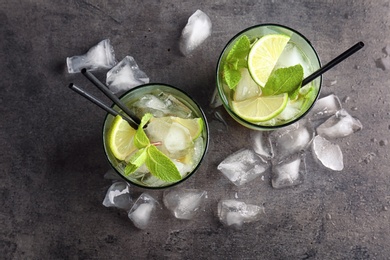 Photo of Flat lay composition with mint julep cocktail and ice cubes on grey background