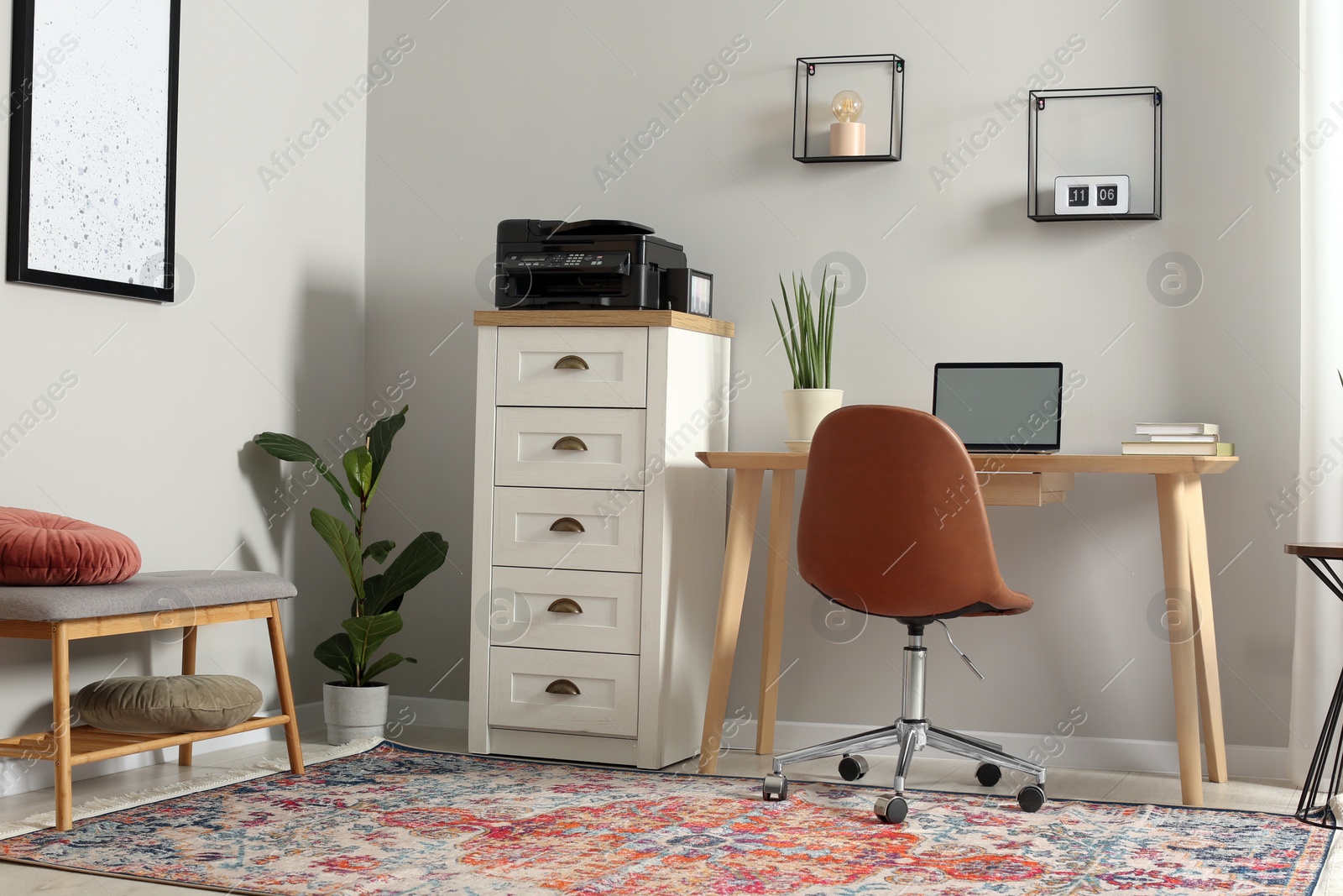 Photo of Stylish room interior with chest of drawers, modern printer and laptop