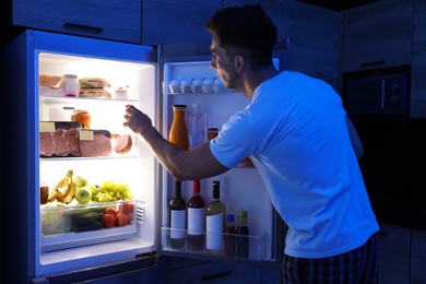 Man taking products out of refrigerator in kitchen at night