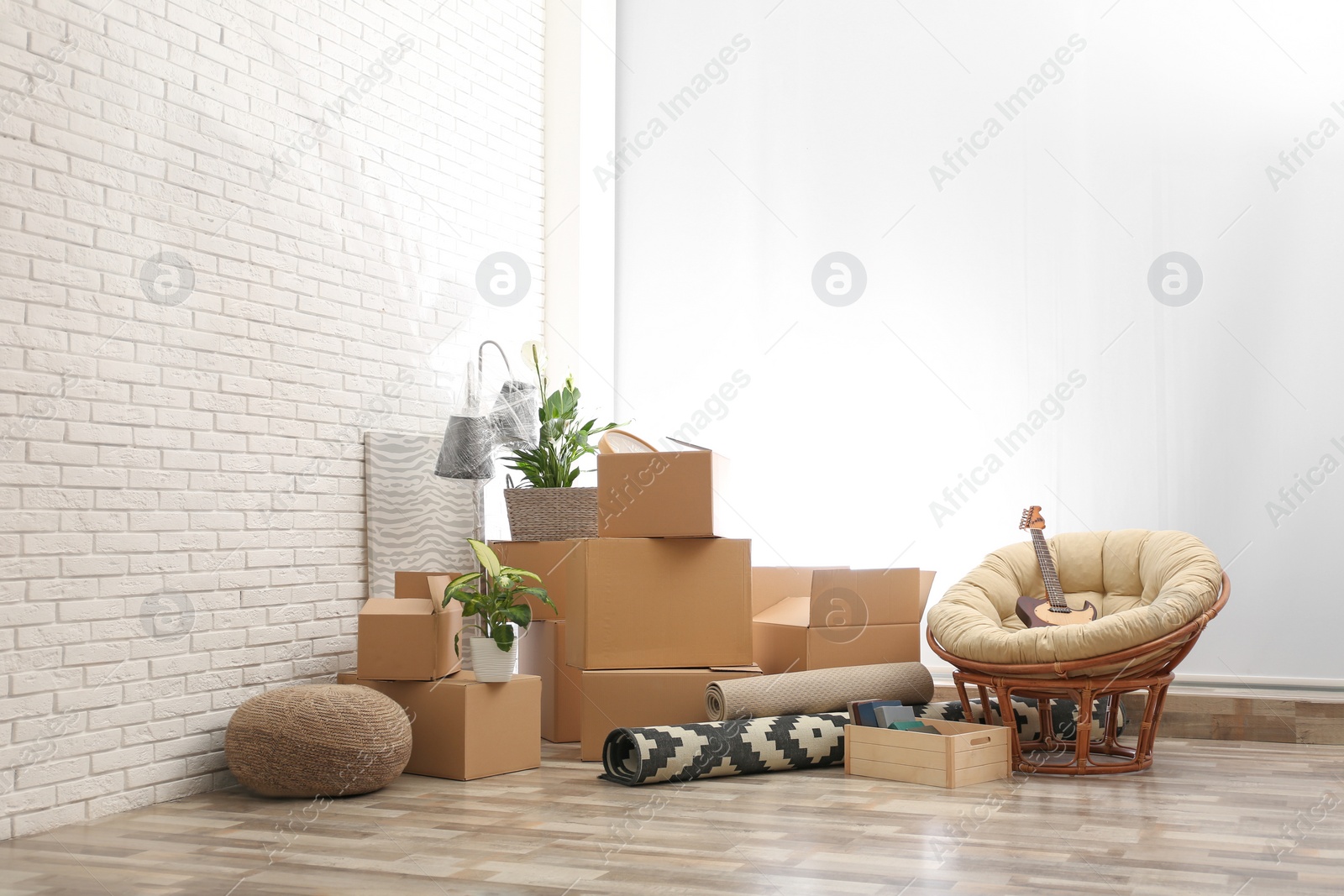 Photo of Moving boxes and stuff near white brick wall in room