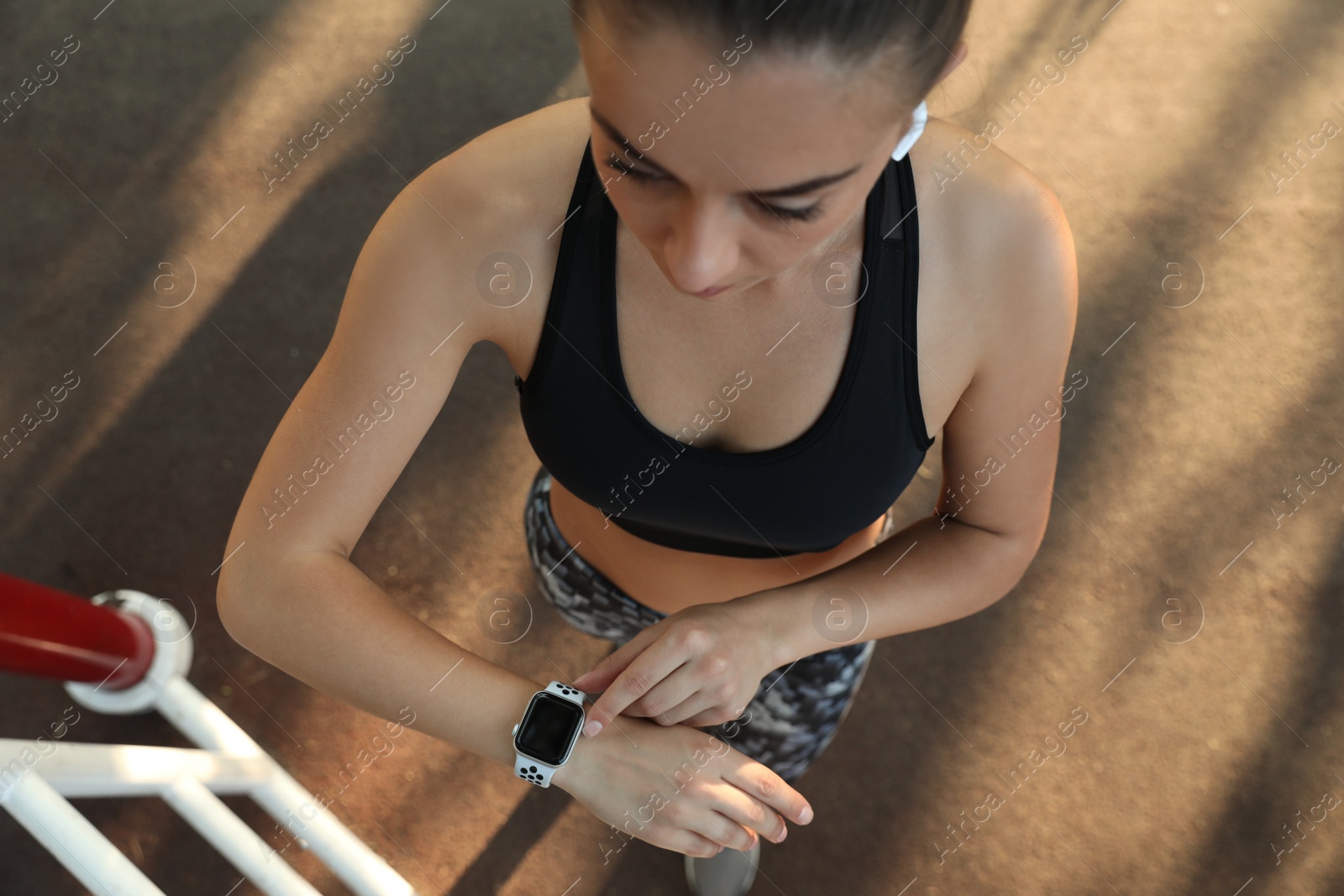 Photo of Woman using modern smart watch during training outdoors, top view