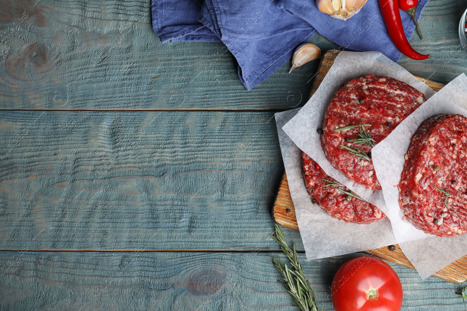 Photo of Flat lay composition with raw meat cutlets for burger on blue wooden table. Space for text