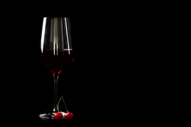 Delicious cherry wine with ripe juicy berries on black background. Space for text