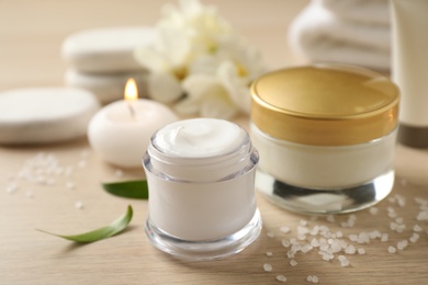 Photo of Composition with skin care products and candle on wooden table, closeup