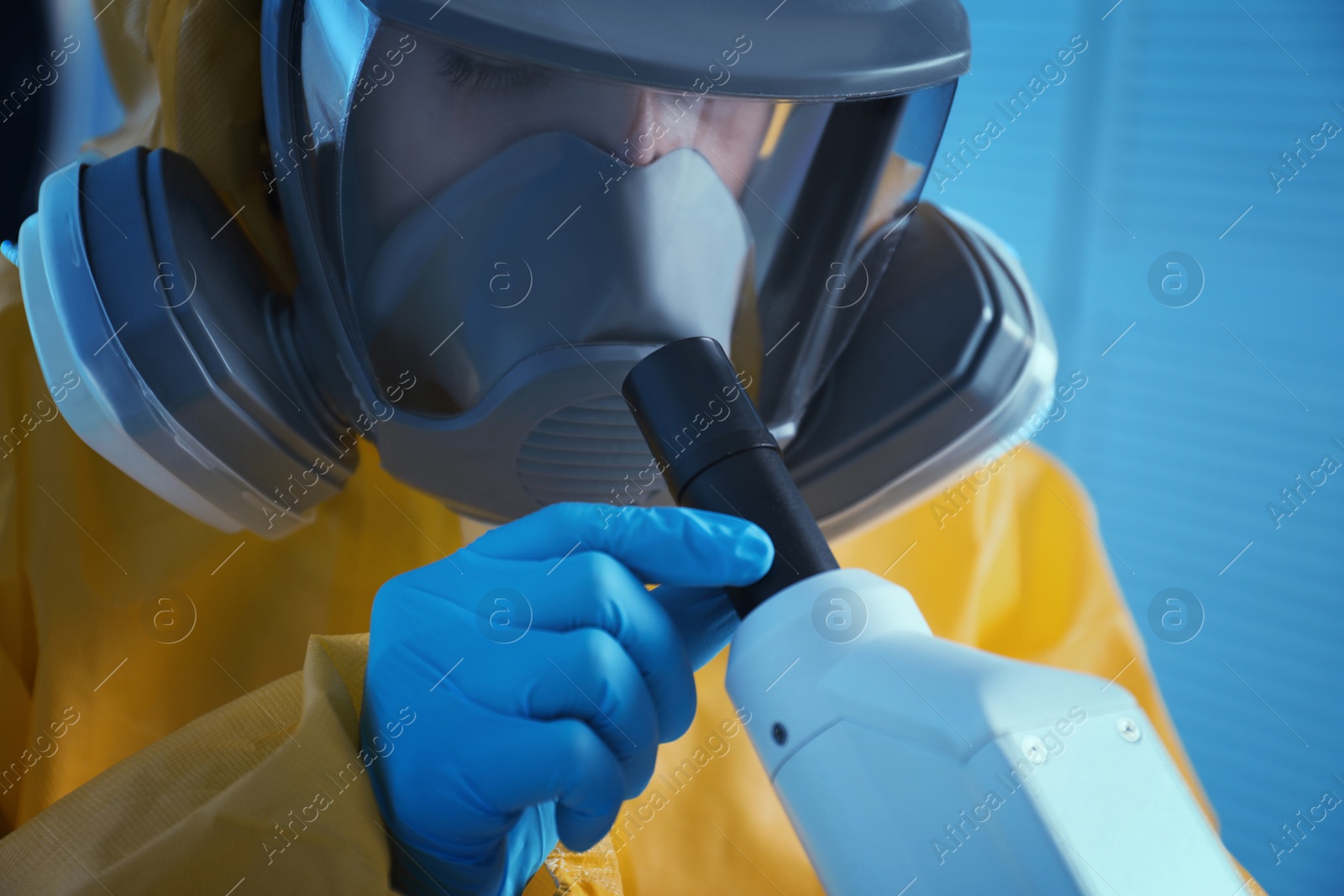 Photo of Scientist in chemical protective suit using microscope at laboratory, closeup. Virus research