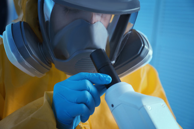 Photo of Scientist in chemical protective suit using microscope at laboratory, closeup. Virus research