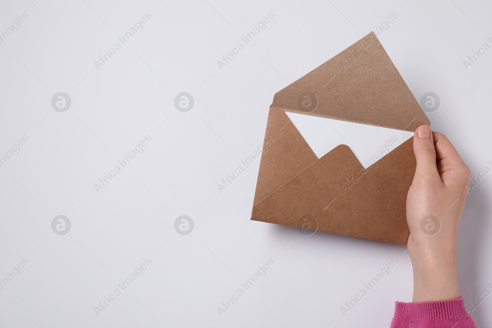 Photo of Woman holding letter envelope with card at white table, top view. Space for text