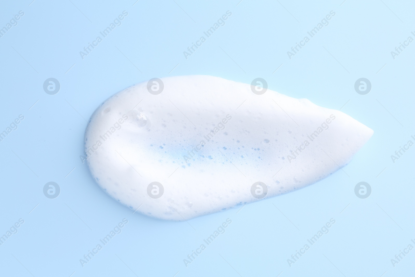 Photo of Sample of fluffy foam on light blue background, top view