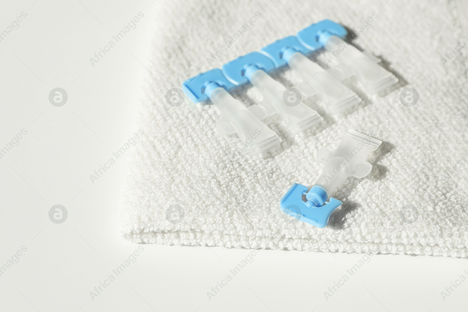 Photo of Single dose eye drops and towel on white table, closeup