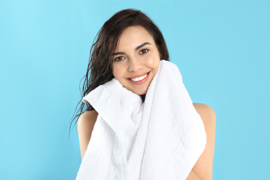 Photo of Young woman wiping face with towel on light blue background