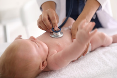 Photo of Doctor examining cute baby with stethoscope indoors, closeup. Health care