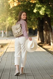 Young woman with stylish beige backpack on city street