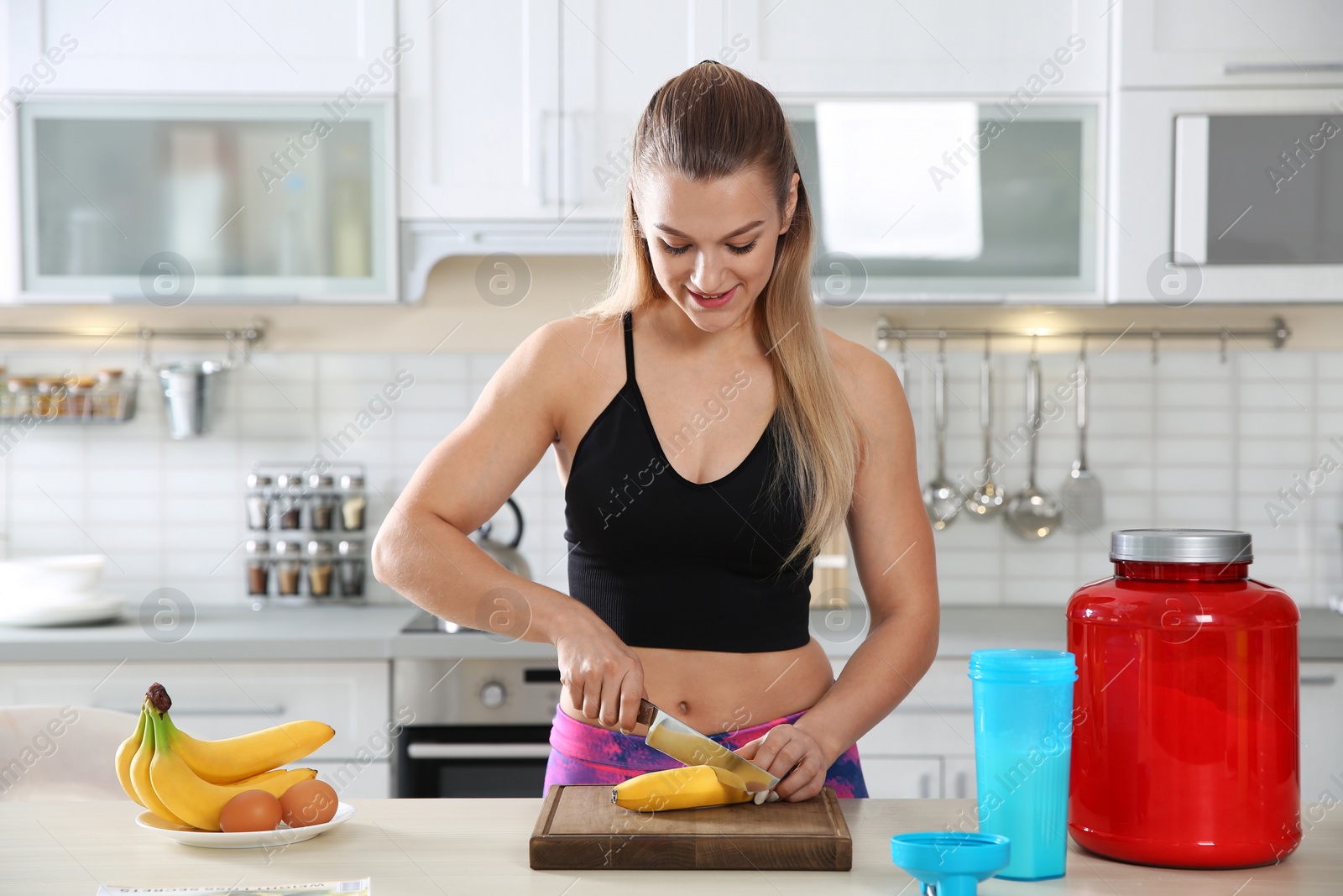 Photo of Young woman preparing protein shake at table in kitchen