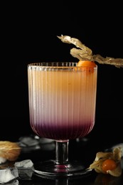 Photo of Refreshing cocktail decorated with physalis fruit on black background