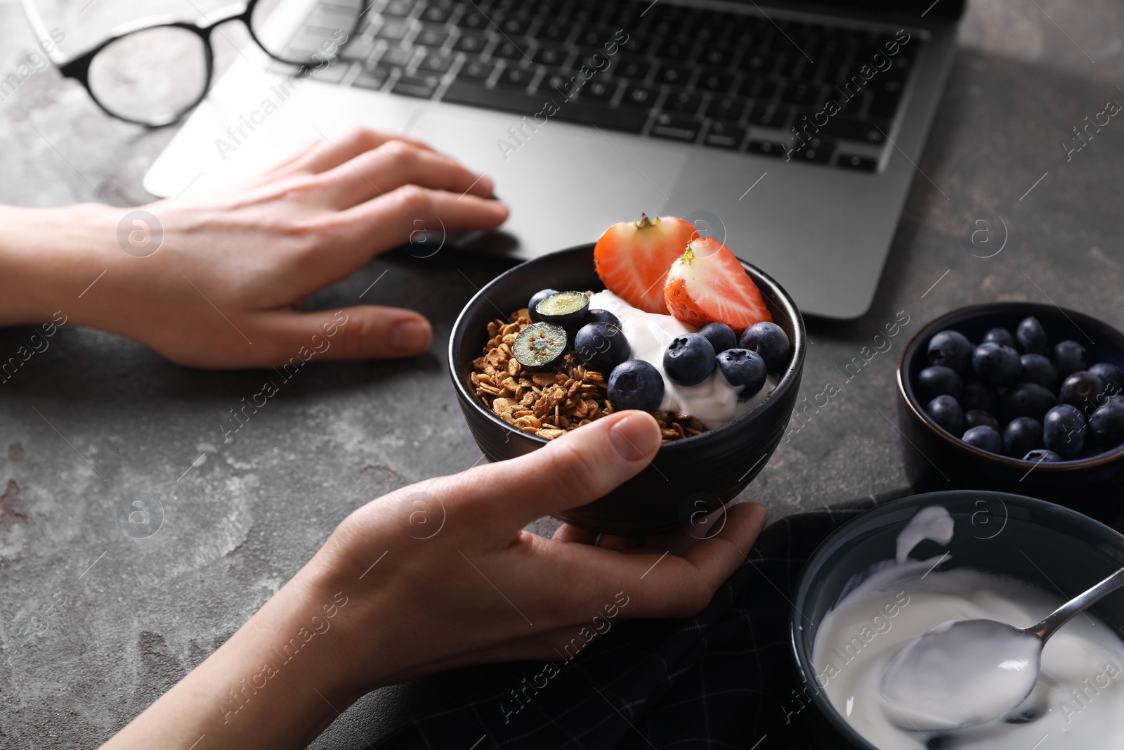 Photo of Woman with tasty granola at workplace, closeup