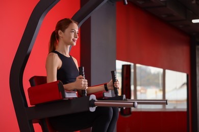 Photo of Athletic young woman training on power tower station in gym