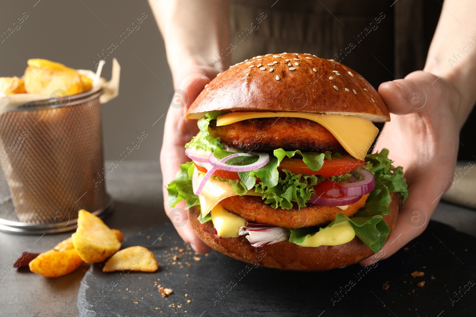 Photo of Woman with double vegetarian burger at table, closeup