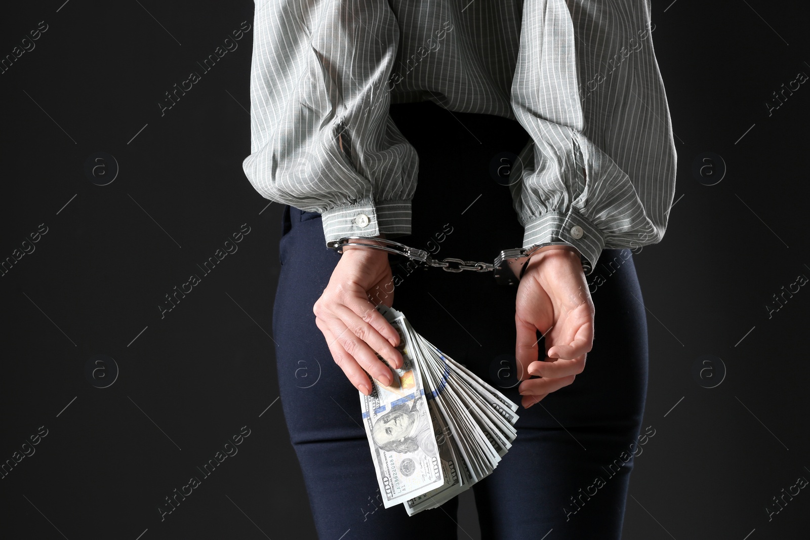 Photo of Woman in handcuffs holding bribe money on black background, closeup