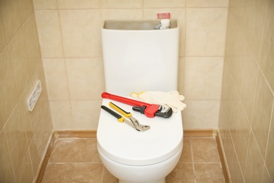 Plumber's tools on toilet seat lid indoors