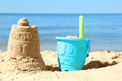 Photo of Beautiful view of beach with sand figure and plastic toys near sea