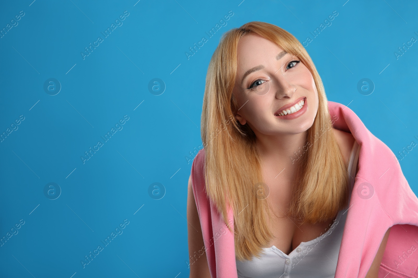 Photo of Beautiful young woman with blonde hair on blue background. Space for text