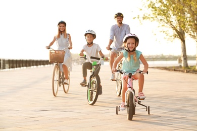 Photo of Happy family riding bicycles outdoors on summer day