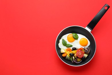 Photo of Tasty fried eggs with vegetables in pan on red background, top view. Space for text