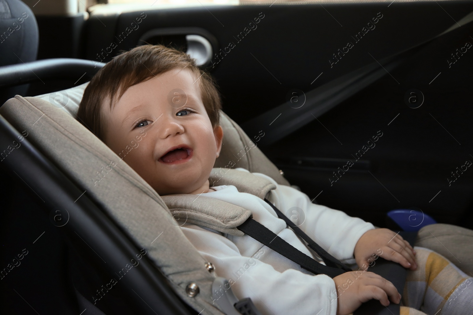 Photo of Cute little boy sitting in child safety seat inside car