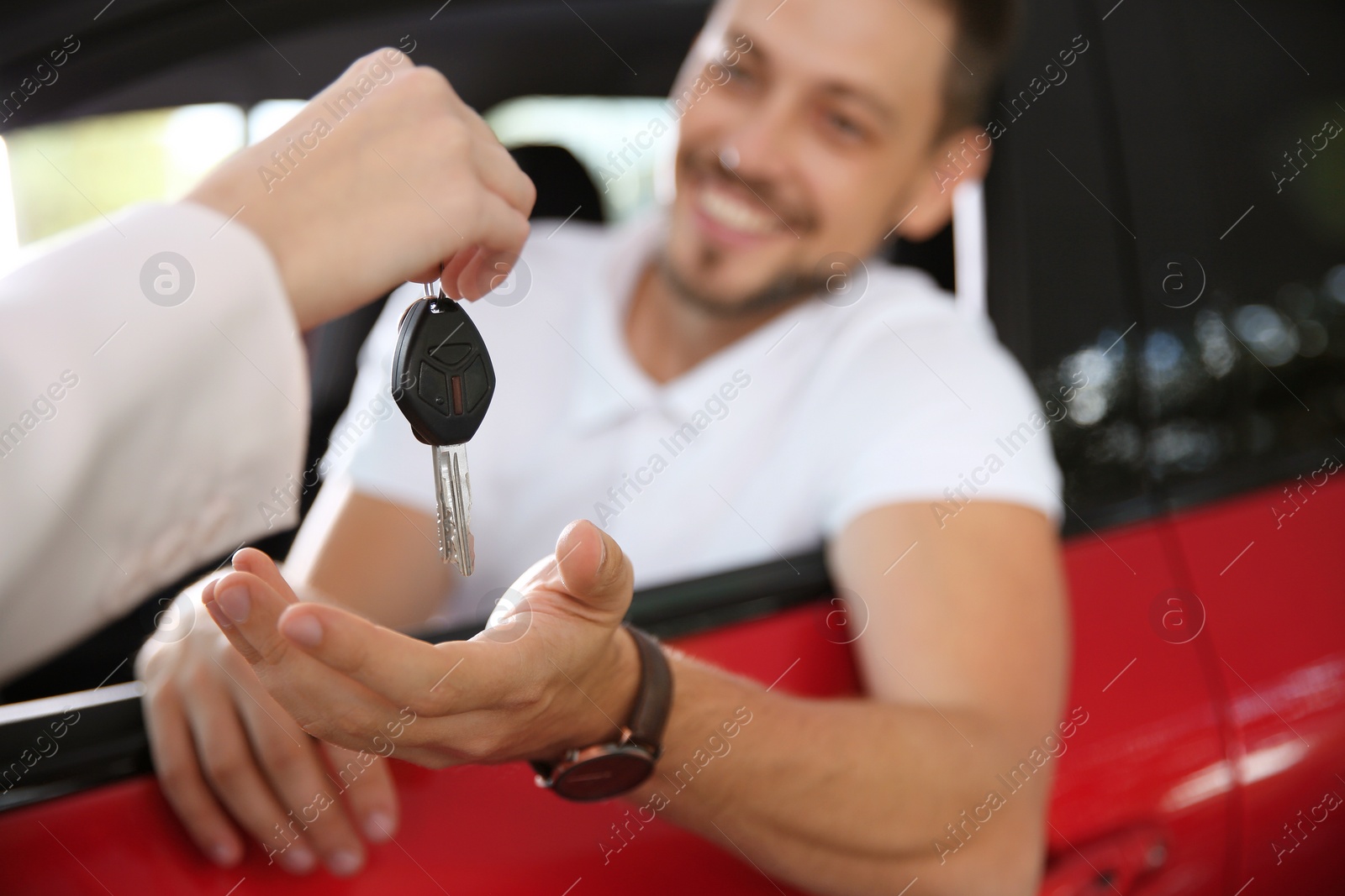 Photo of Female salesperson giving car key to man in new auto, closeup