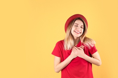 Portrait of woman holding hands near heart on color background. Space for text