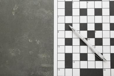 Photo of Blank crossword and pencil on grey table, top view. Space for text