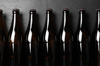 Bottles of beer on grey table, flat lay