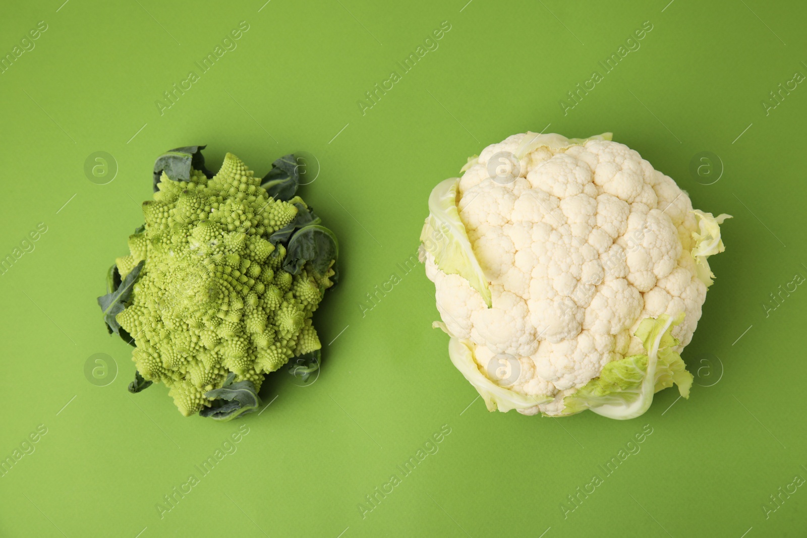 Photo of Fresh Romanesco broccoli and cauliflower on green background, flat lay